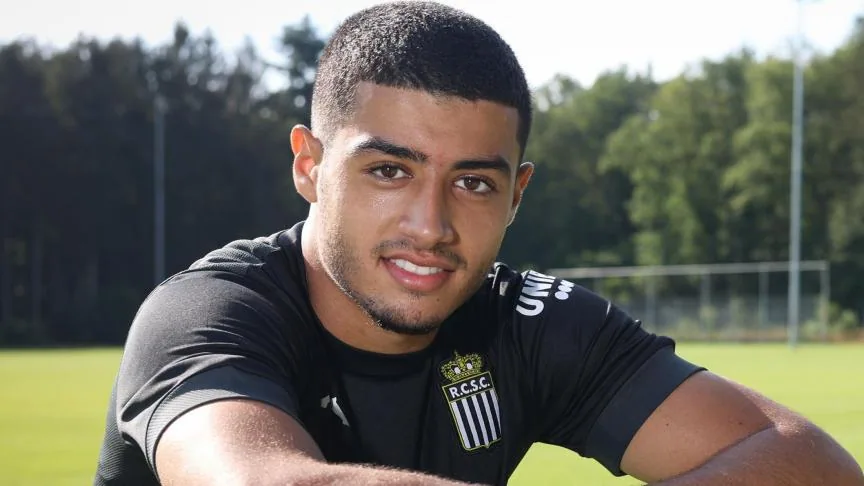 Anass Zaroury smiling on a training pitch in a black shirt.