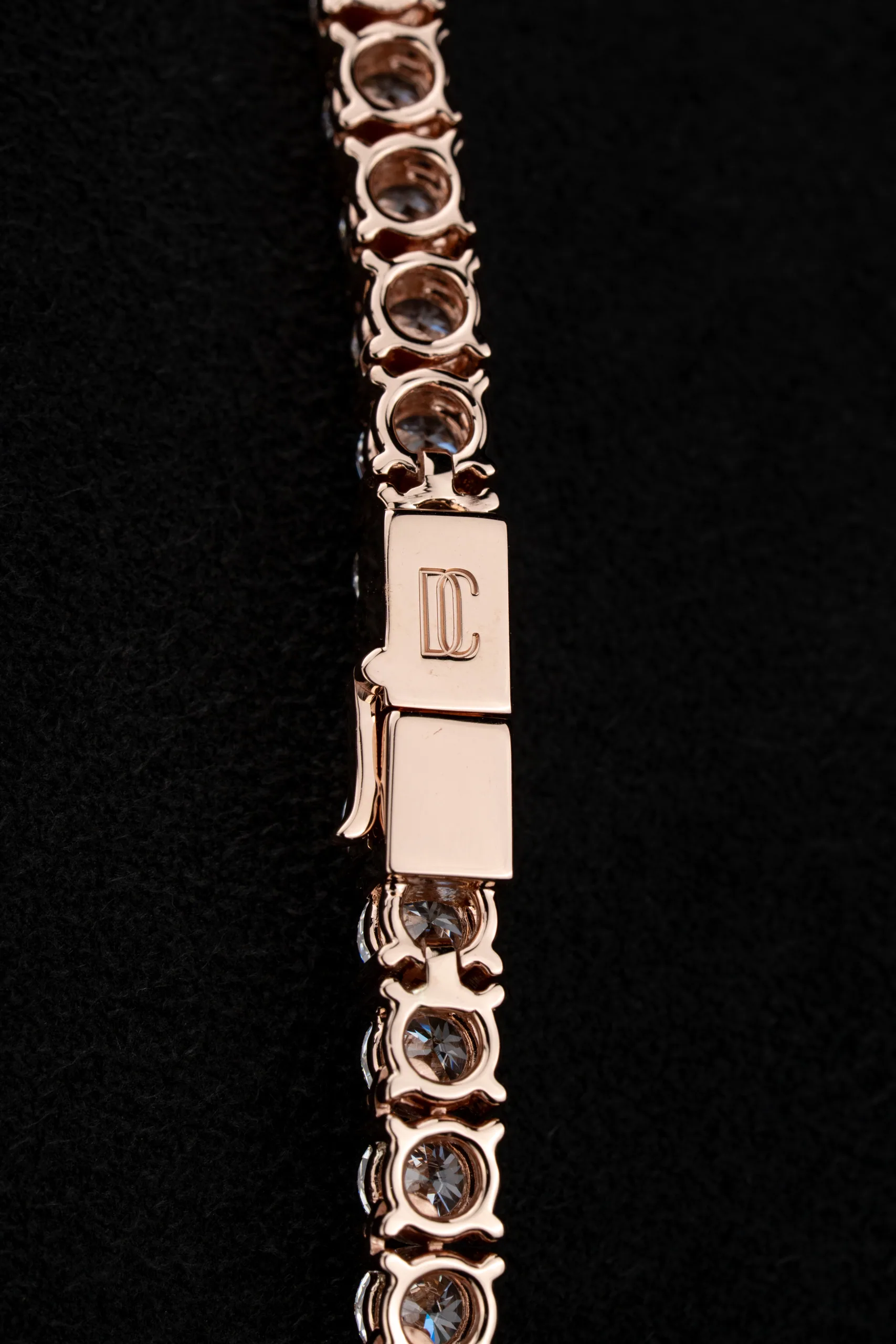Extreme close-up of the pendant's initials gathering light.