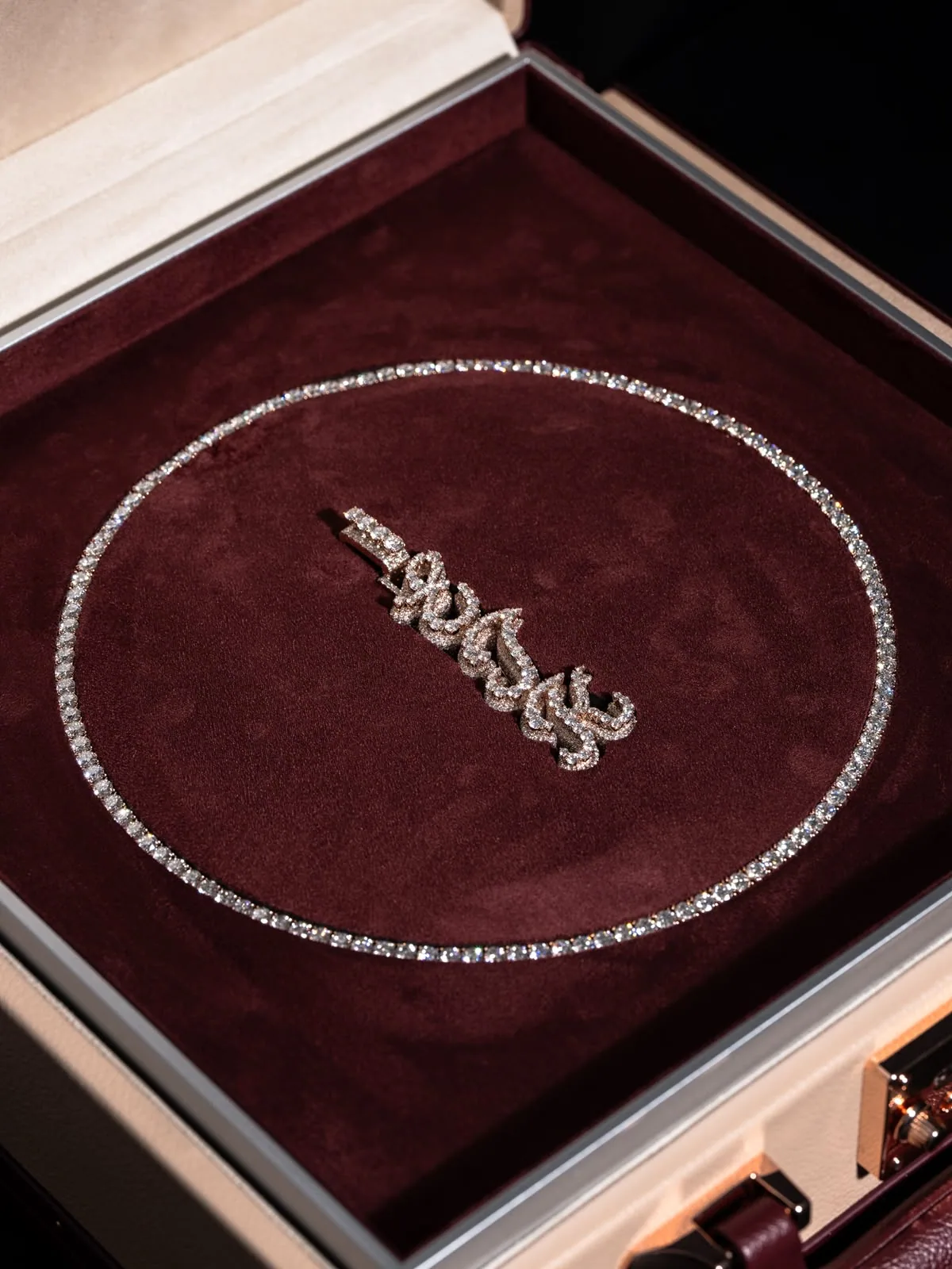 The écrin open, a diamond necklace laid in an oval on burgundy velvet.