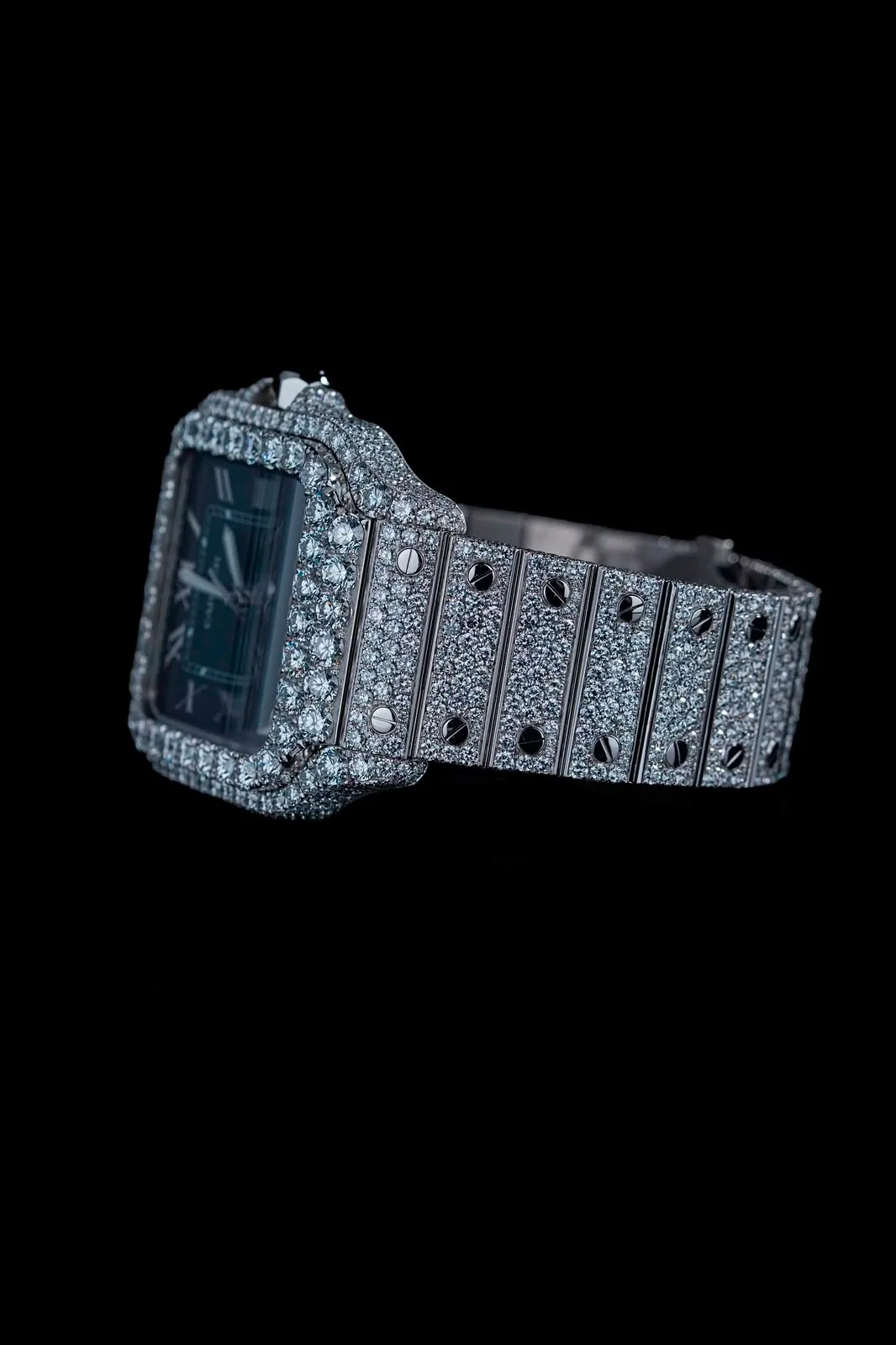 The watch in profile, the diamond-set bracelet links and their polished screws running into shadow.