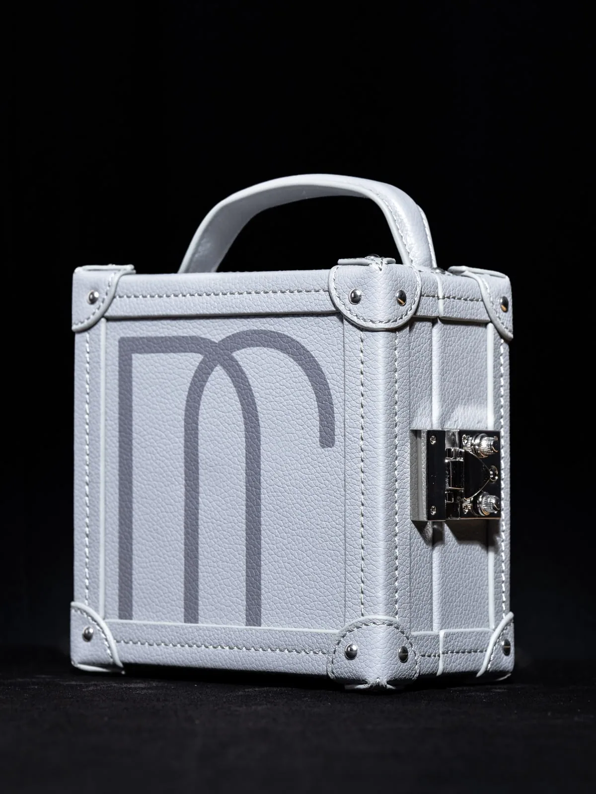 The white écrin head-on, handle raised and corners guarded.