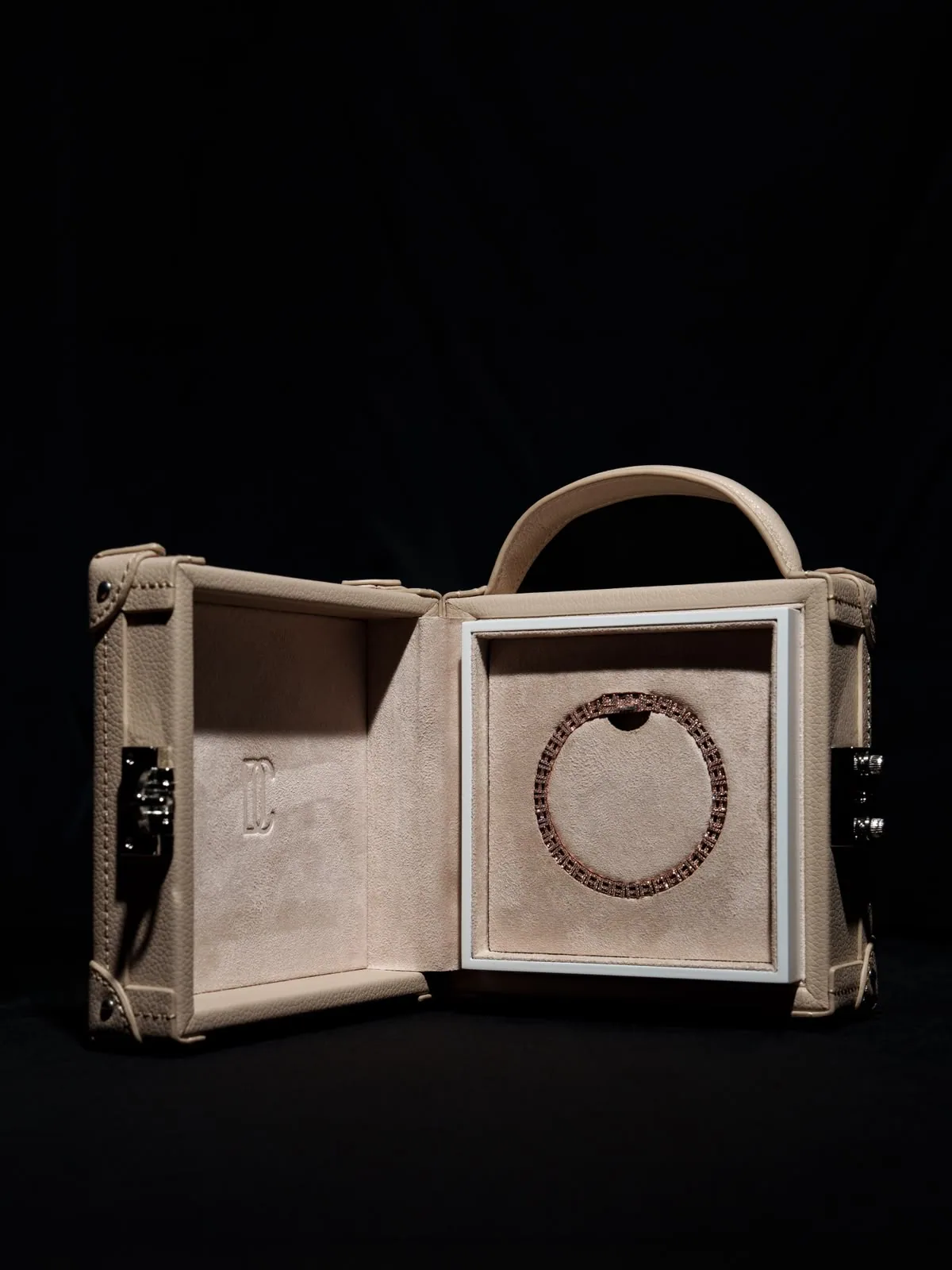 The écrin open, a paved chain coiled in a circle on its pale suede display panel.