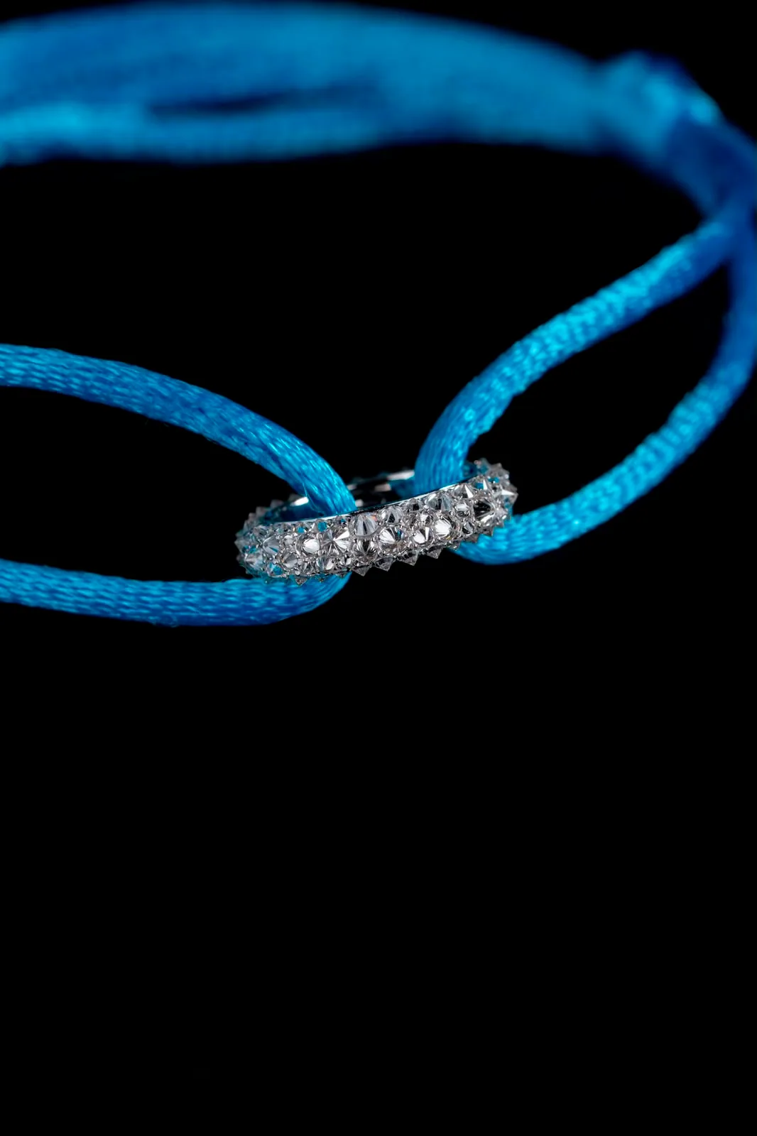 The bracelet laid flat, the cord's loops meeting through the diamond-set ring.