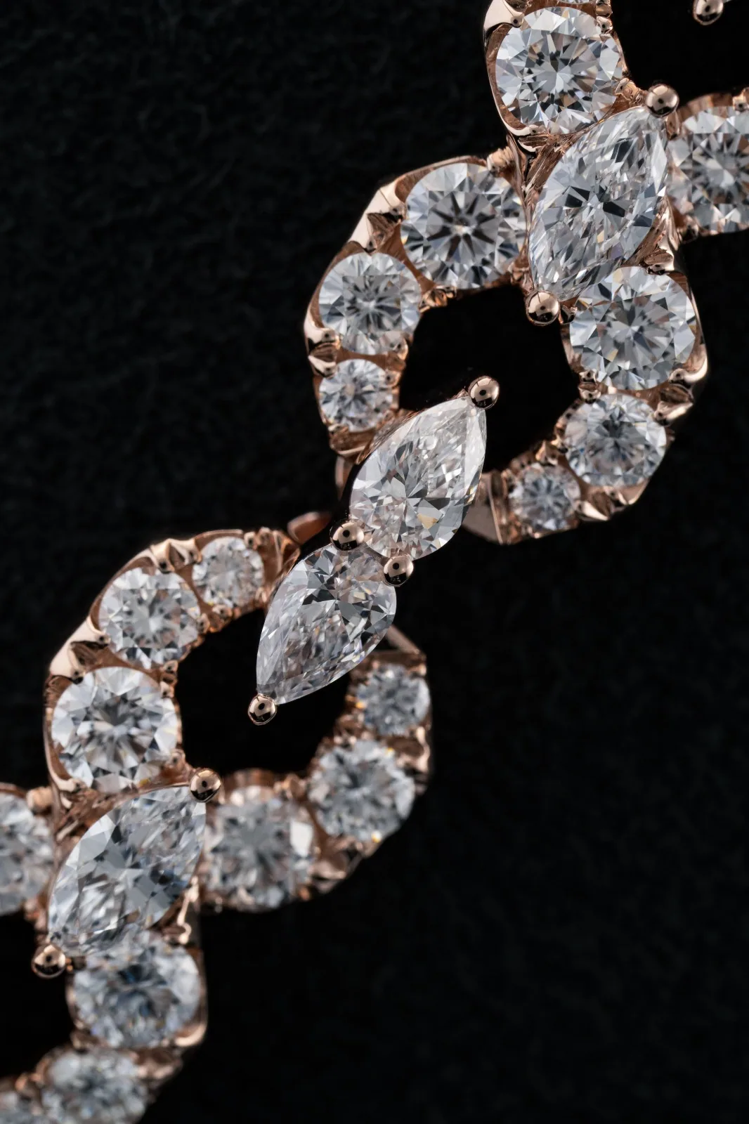Macro of two links, round diamonds framing a marquise stone at the centre.