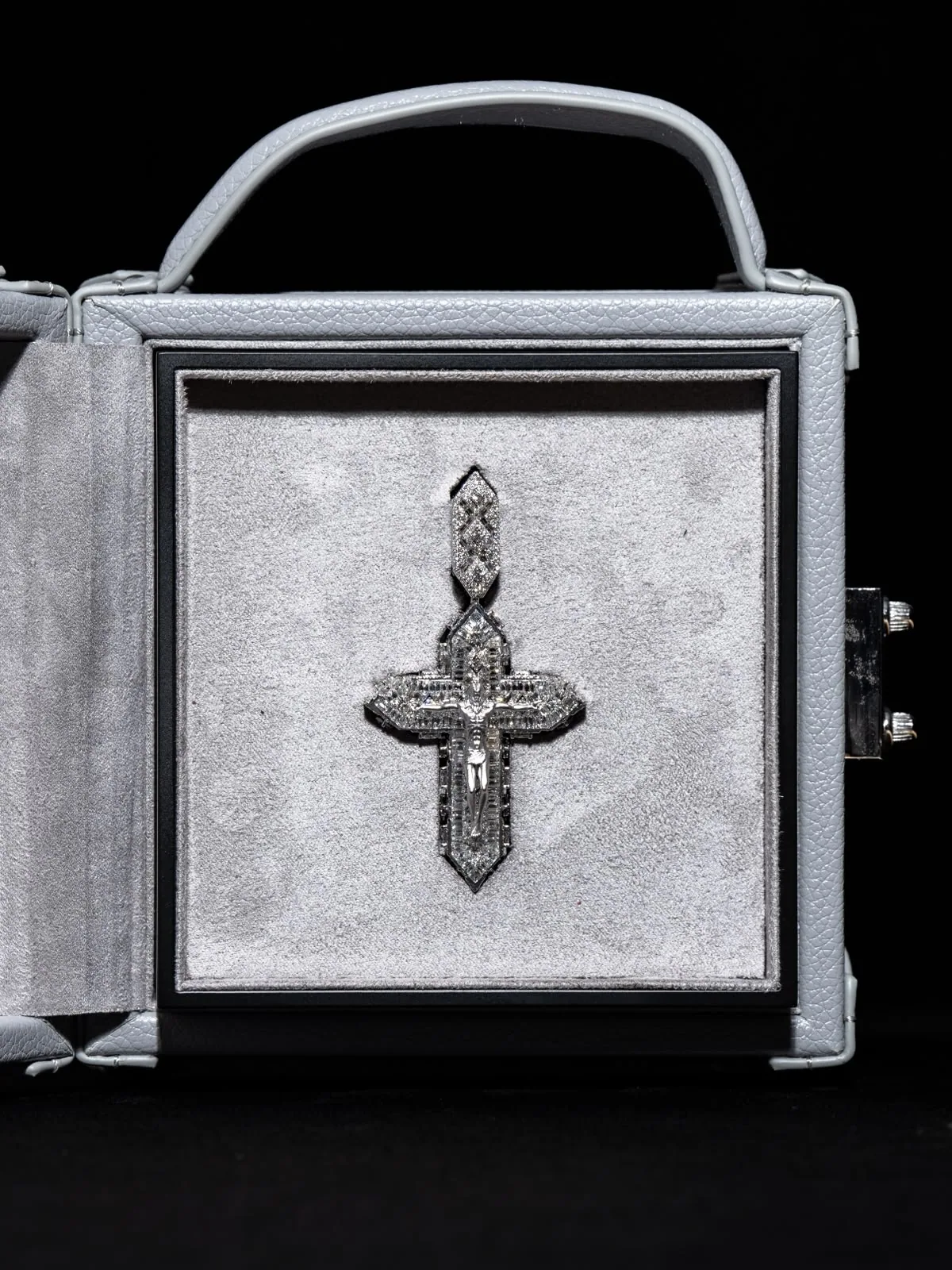 The écrin open, a diamond cross displayed against its white suede panel.
