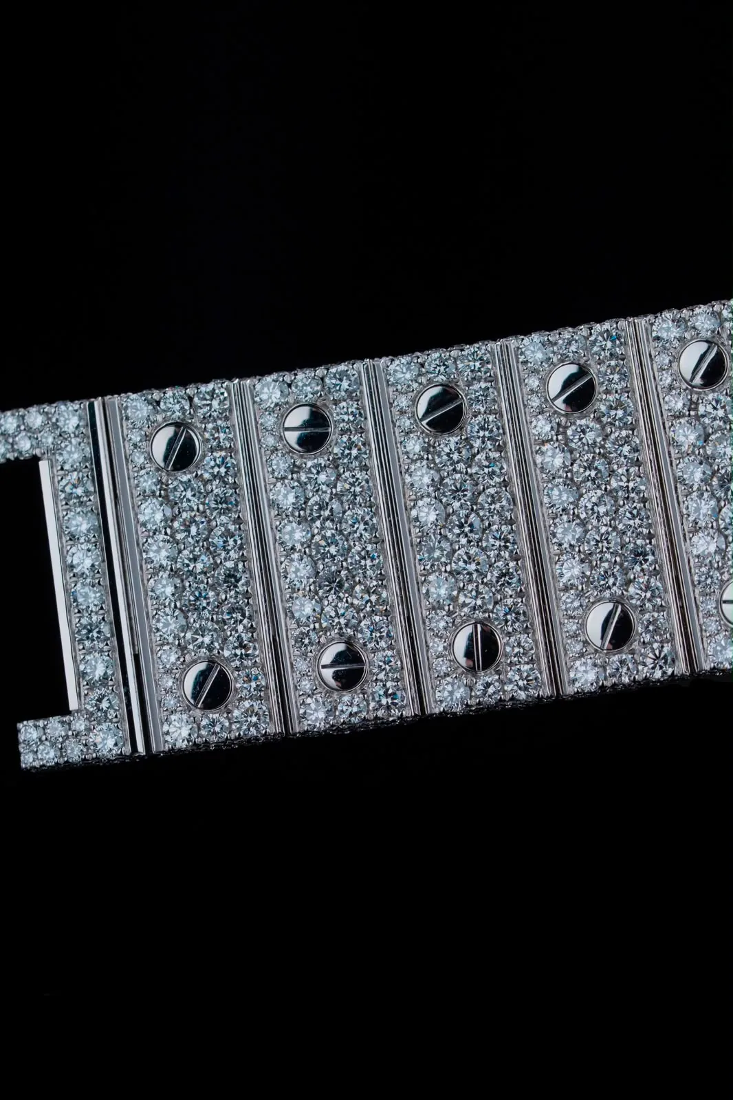 Close on the bracelet links, each paved with diamonds between two polished screws.