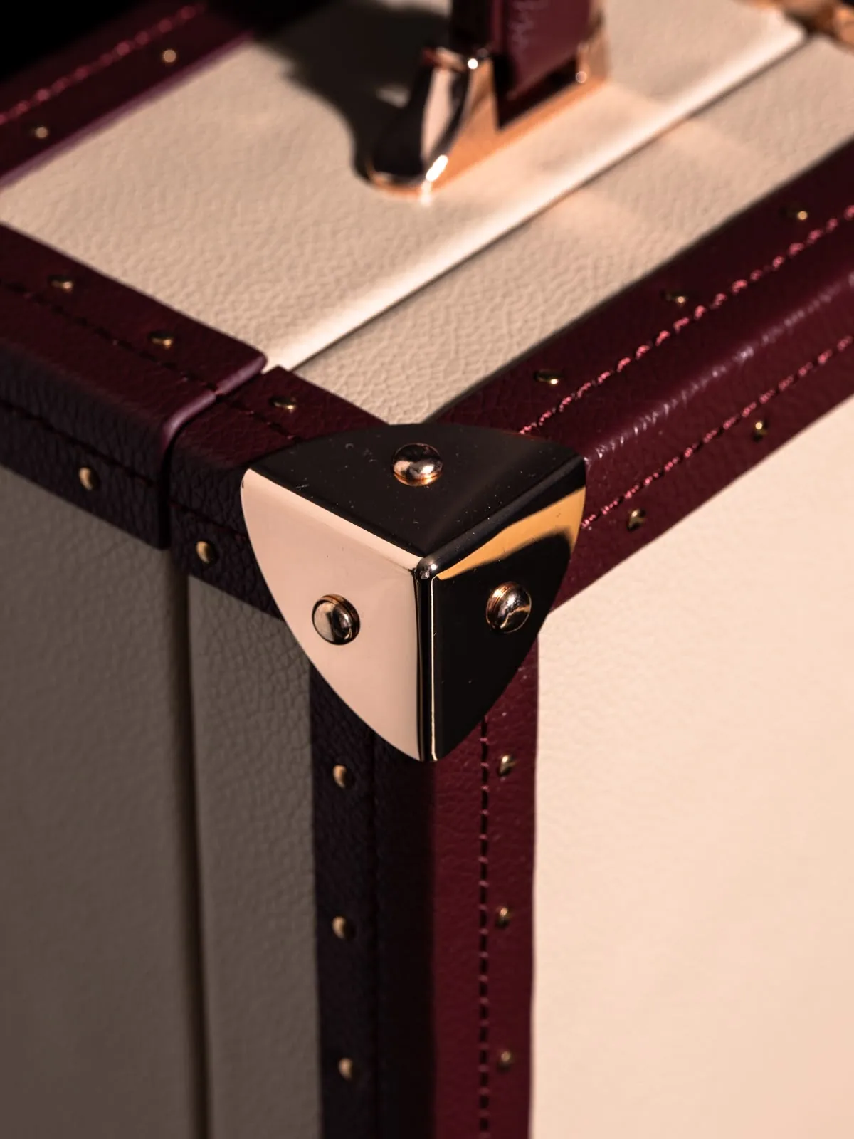 Macro of a guarded corner where the burgundy trim meets the cream panel.