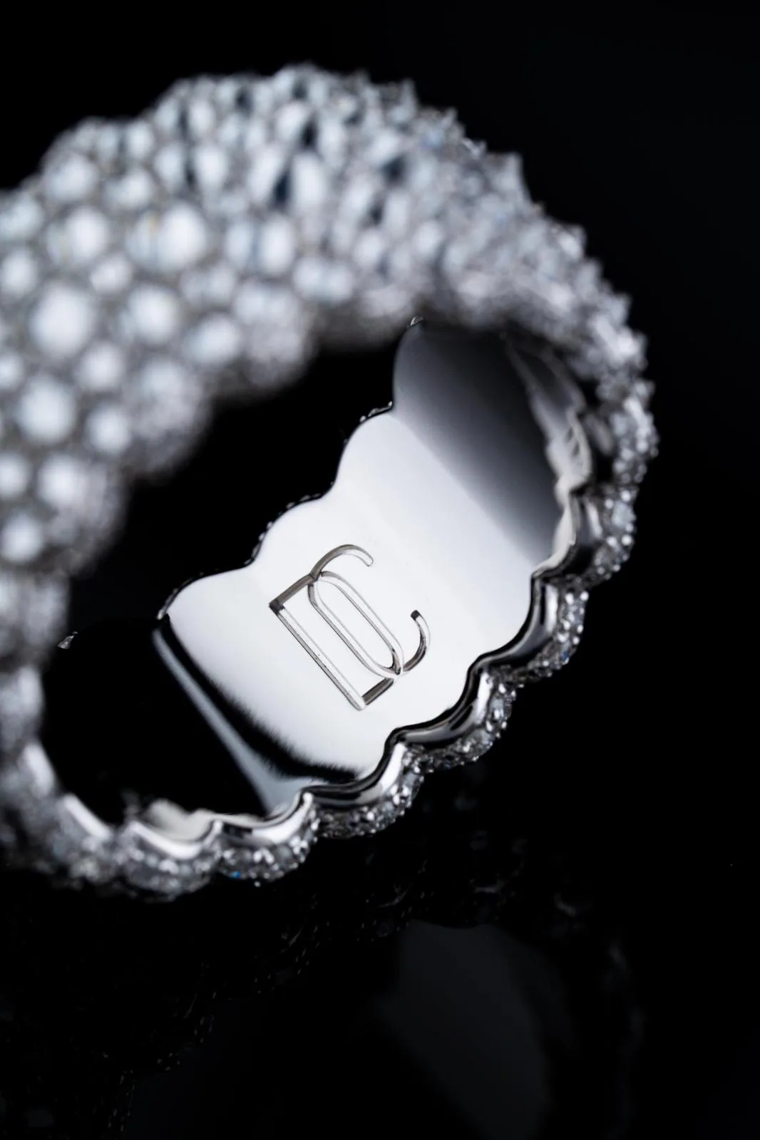 The polished inside of the band, engraved with the maison's monogram, its scalloped edge set with small diamonds.