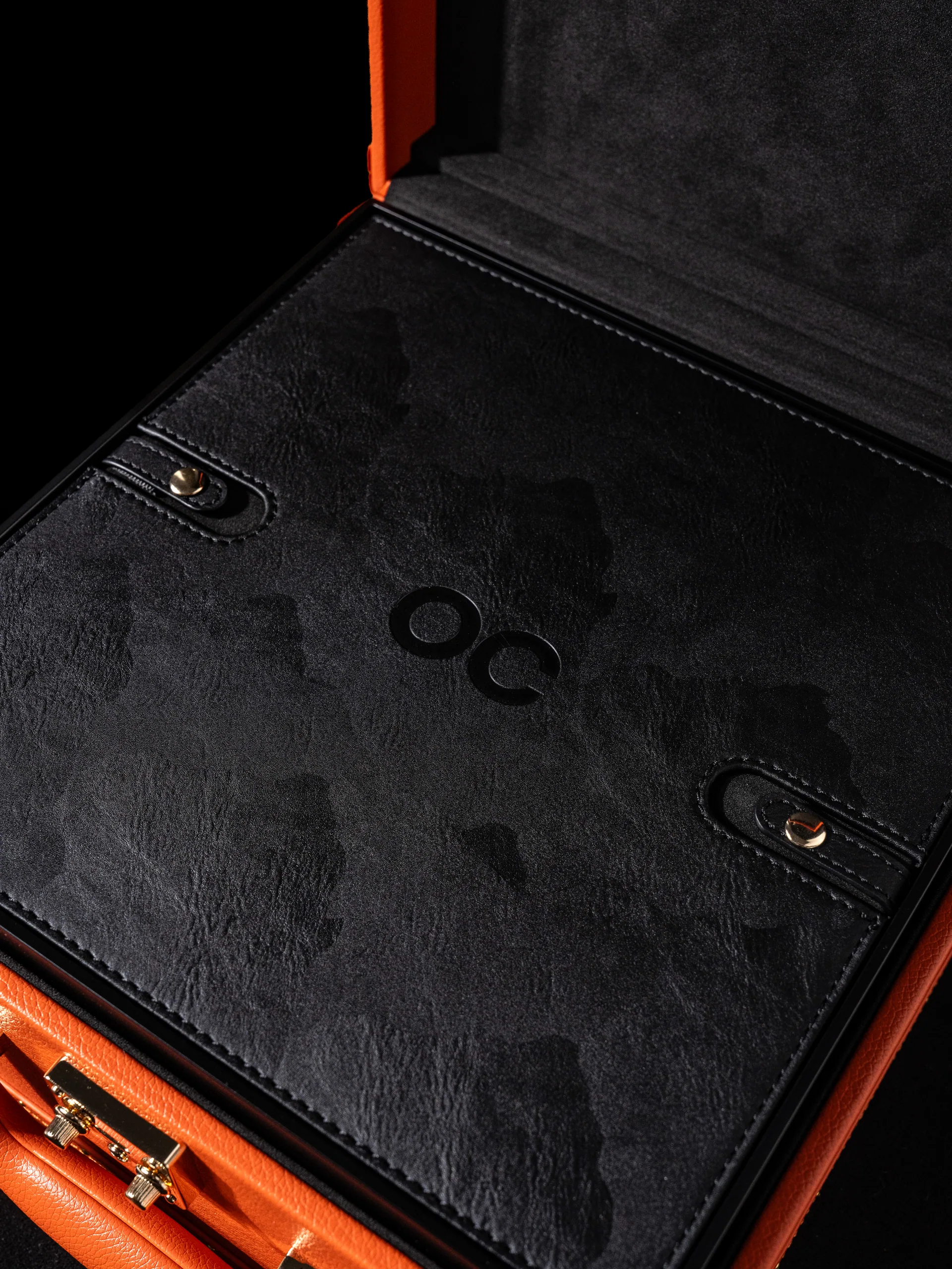The open lid in dark suede, embossed with a monogram.