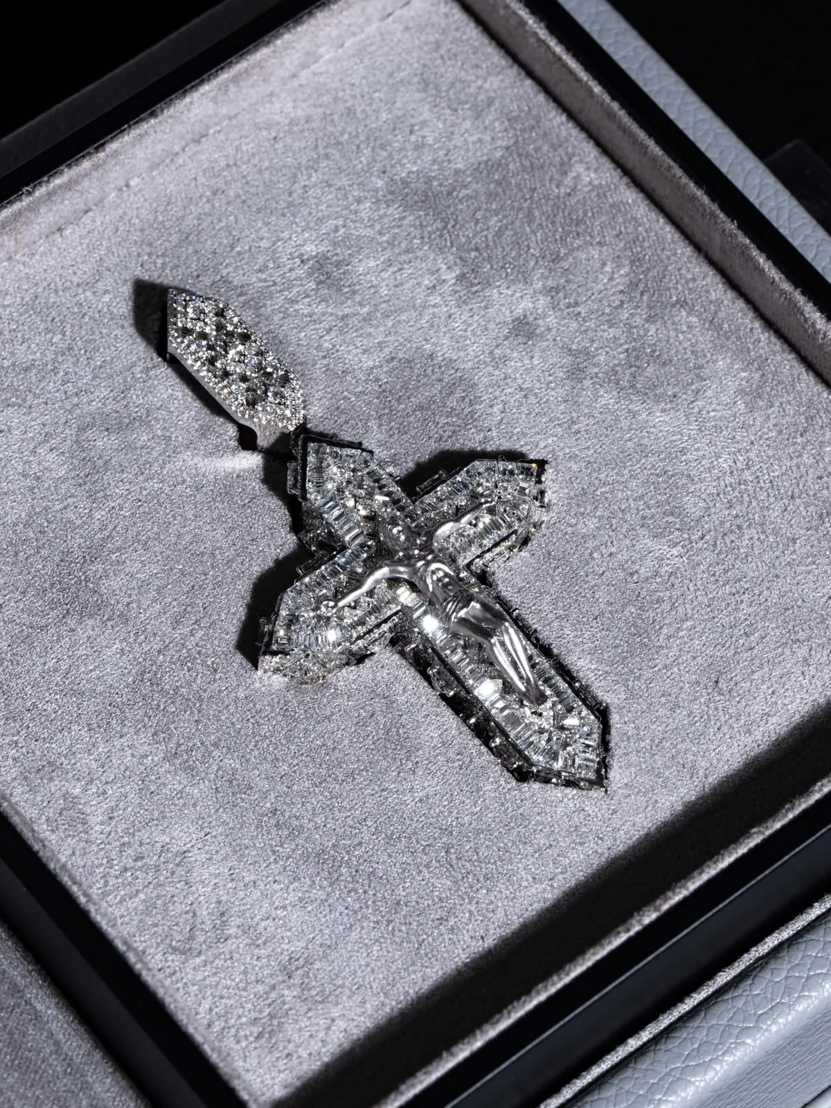 Macro of the diamond cross on white suede, its stones scattering light.
