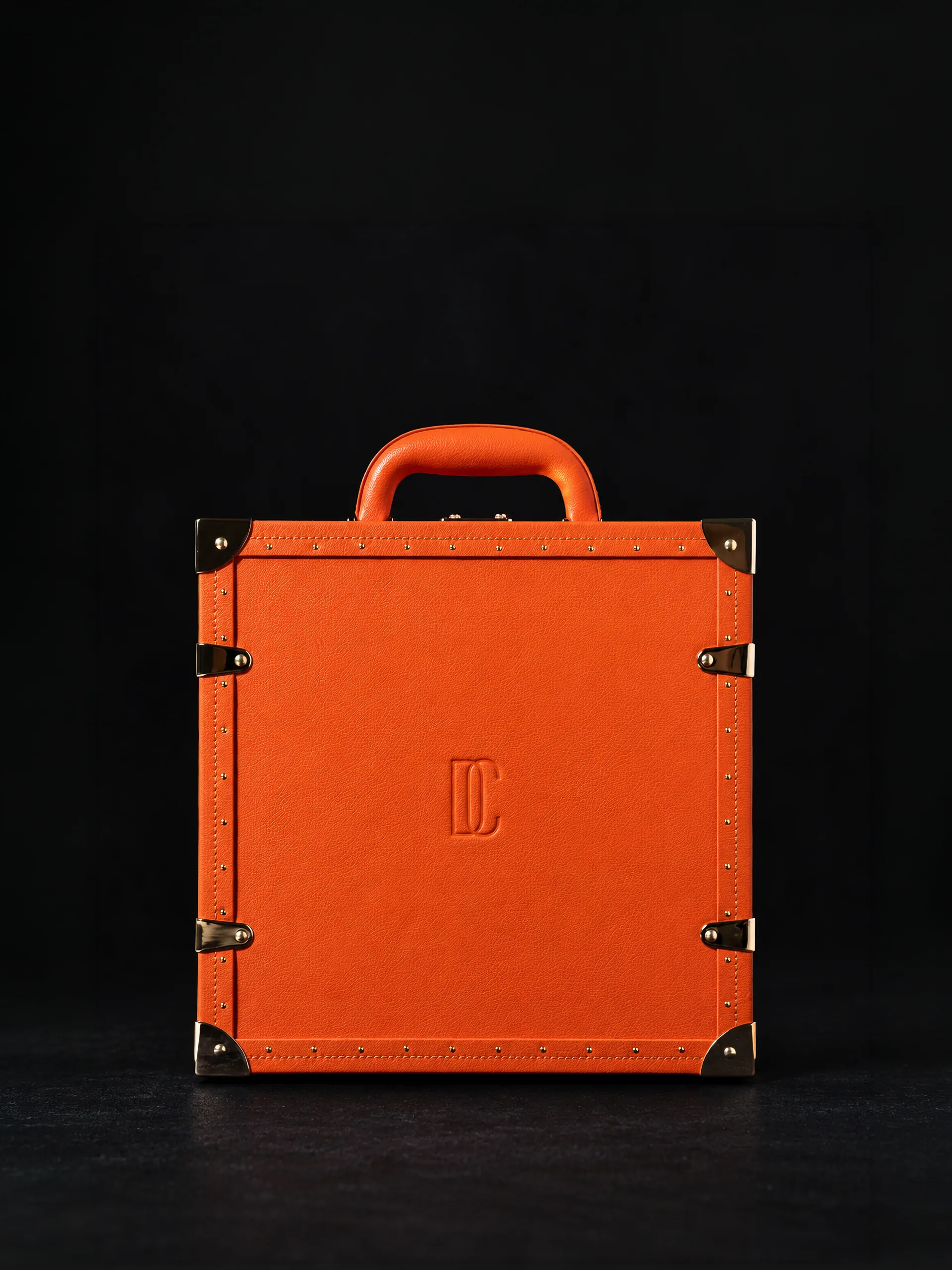 The trunk closed, plain orange leather with guarded corners and clasps.