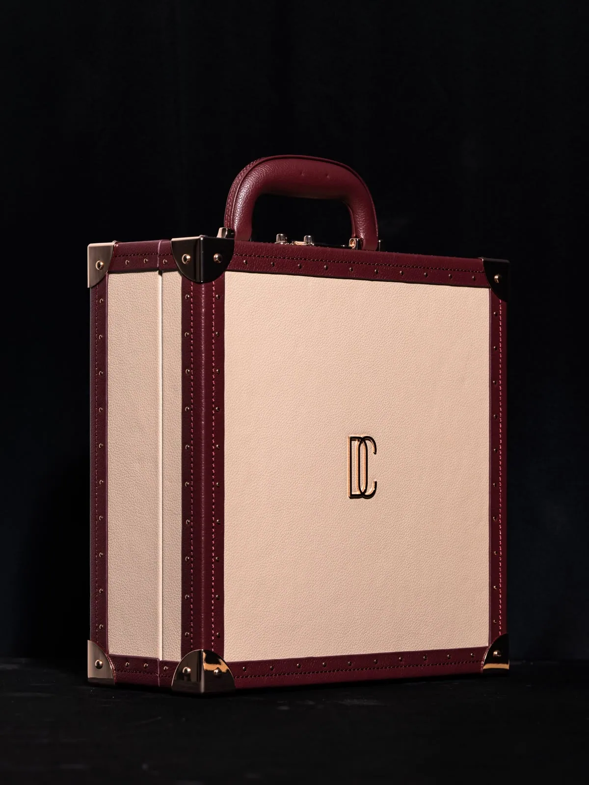 The écrin turned, the gilt monogram catching light on its cream side.