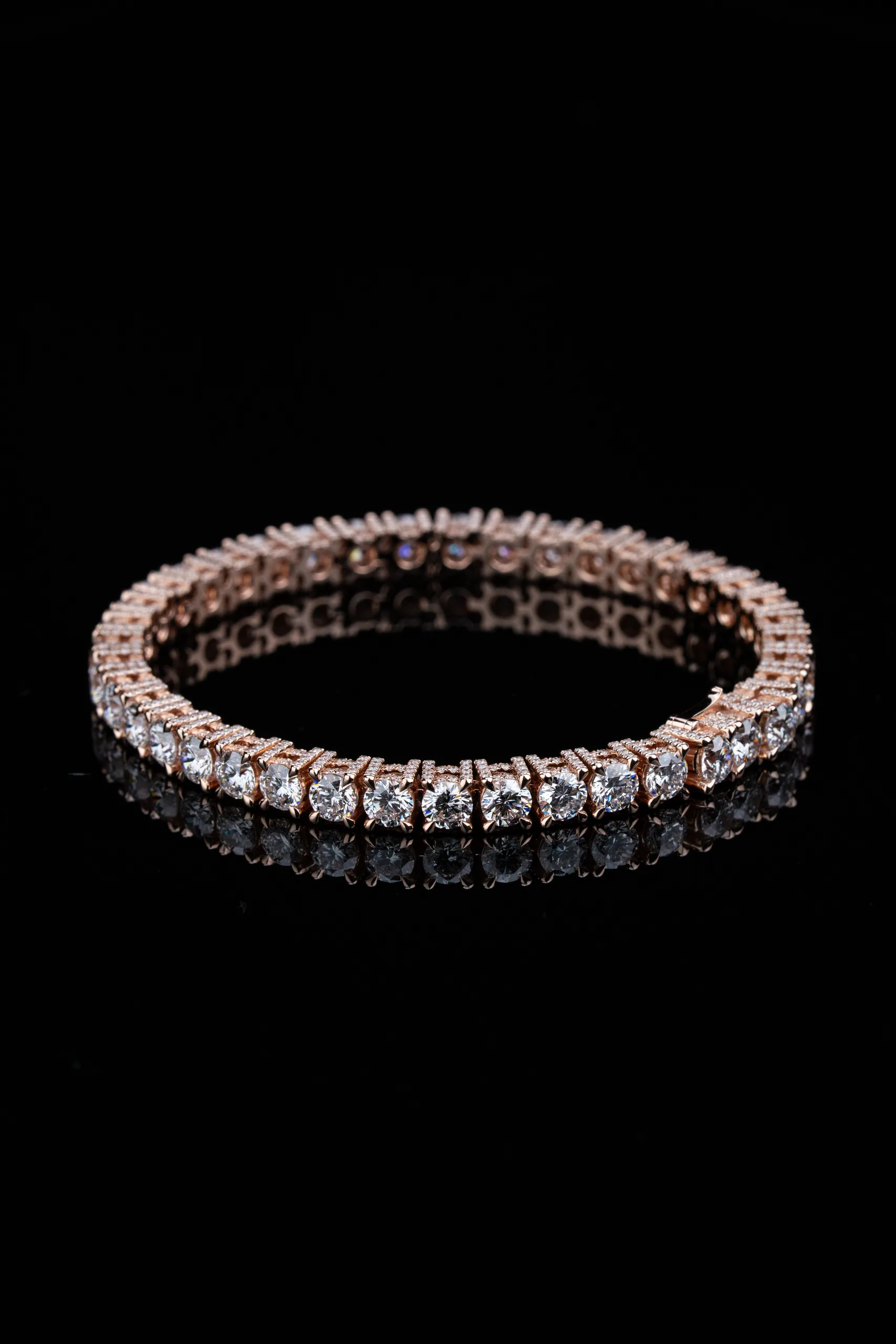 The tennis bracelet catching low warm light against near-black.