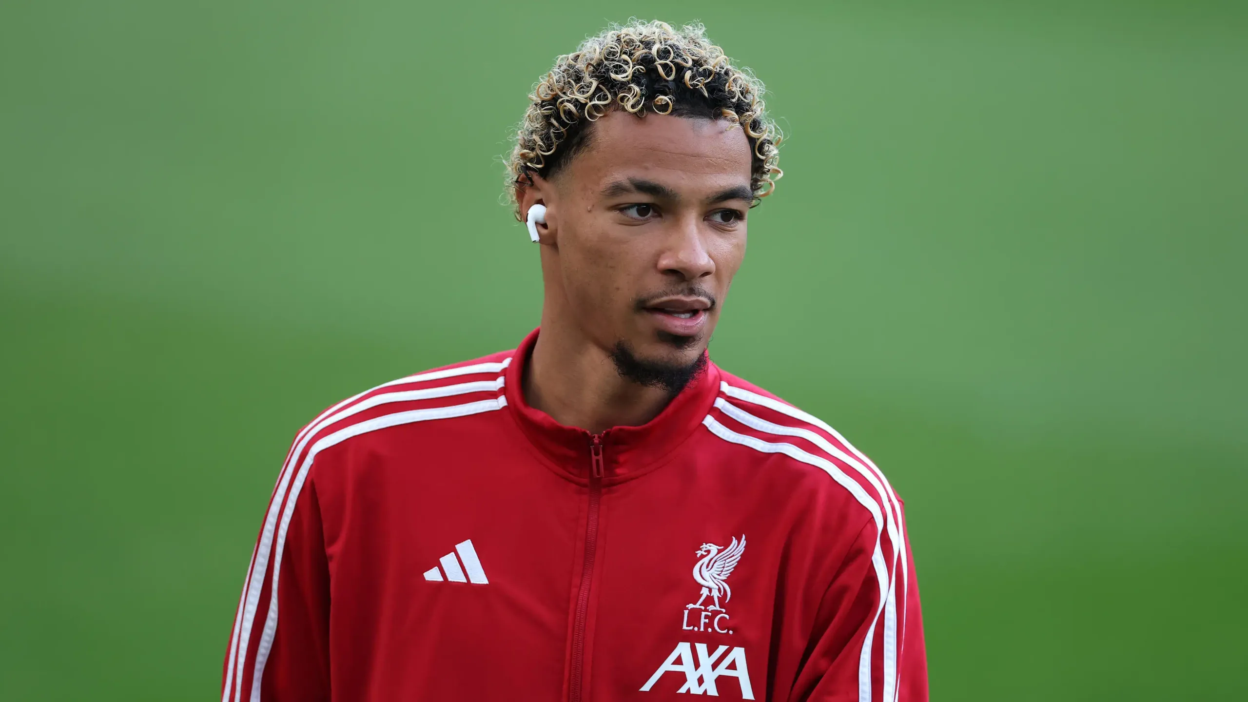 Hugo Ekitike in a red training jacket, his blond curls lit by the sun.