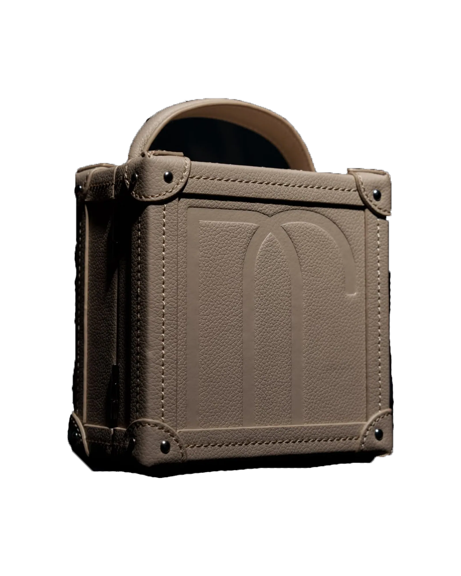 A taupe leather trunk cut out against near-black, a monogram embossed on its front and a handle on its lid.
