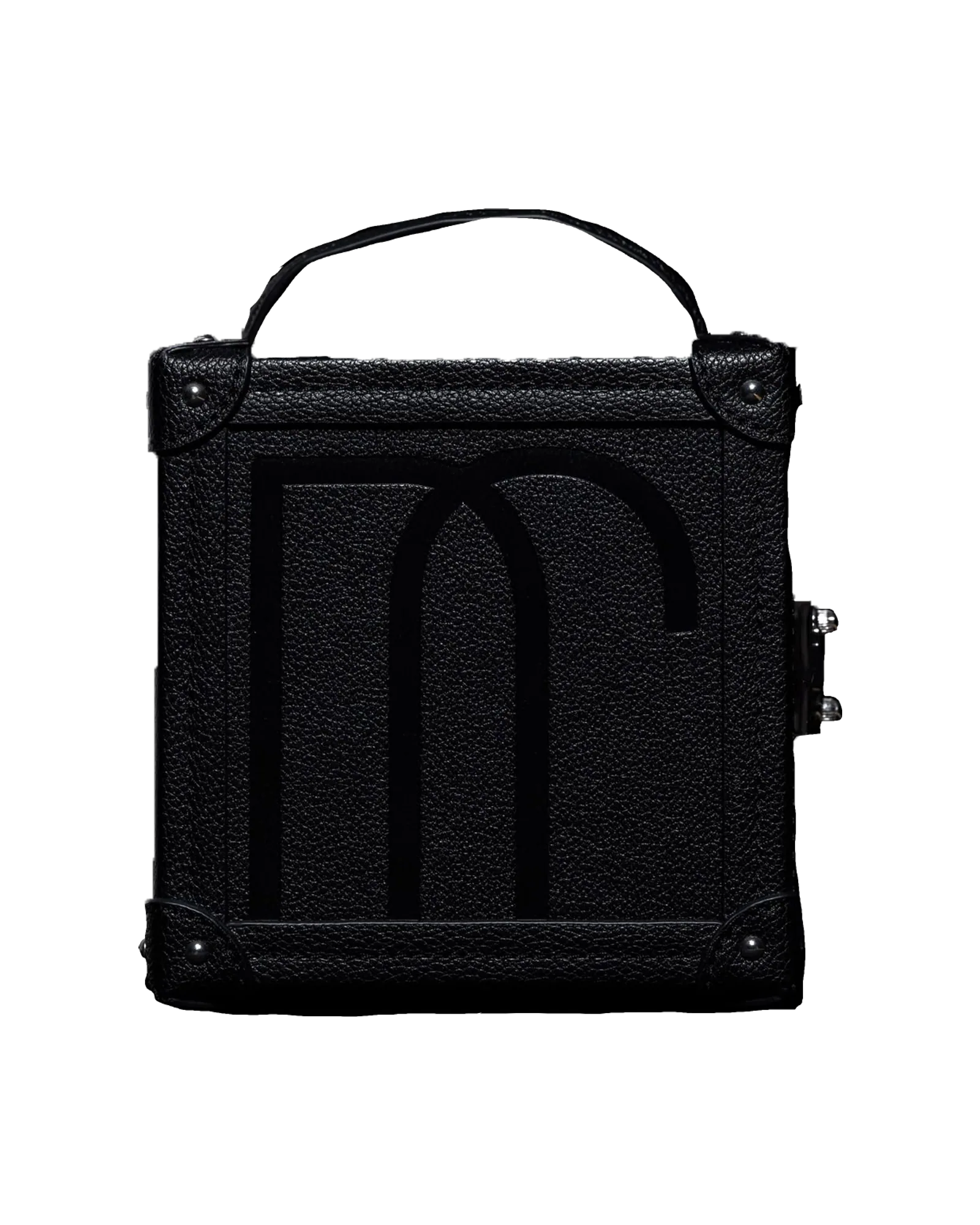A black leather trunk cut out against near-black, a monogram embossed across its front and silver guards at its corners.