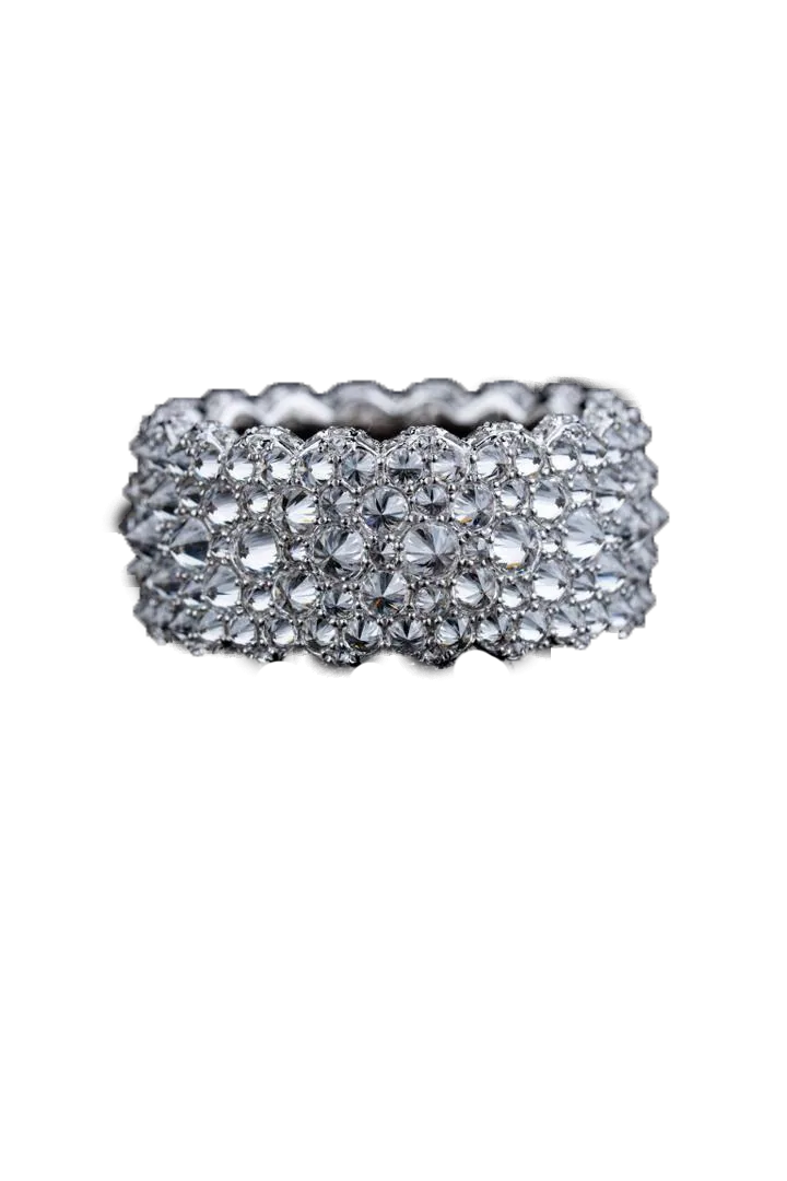 A wide white-gold band cut out against near-black, its scalloped surface covered in diamonds set point upward.