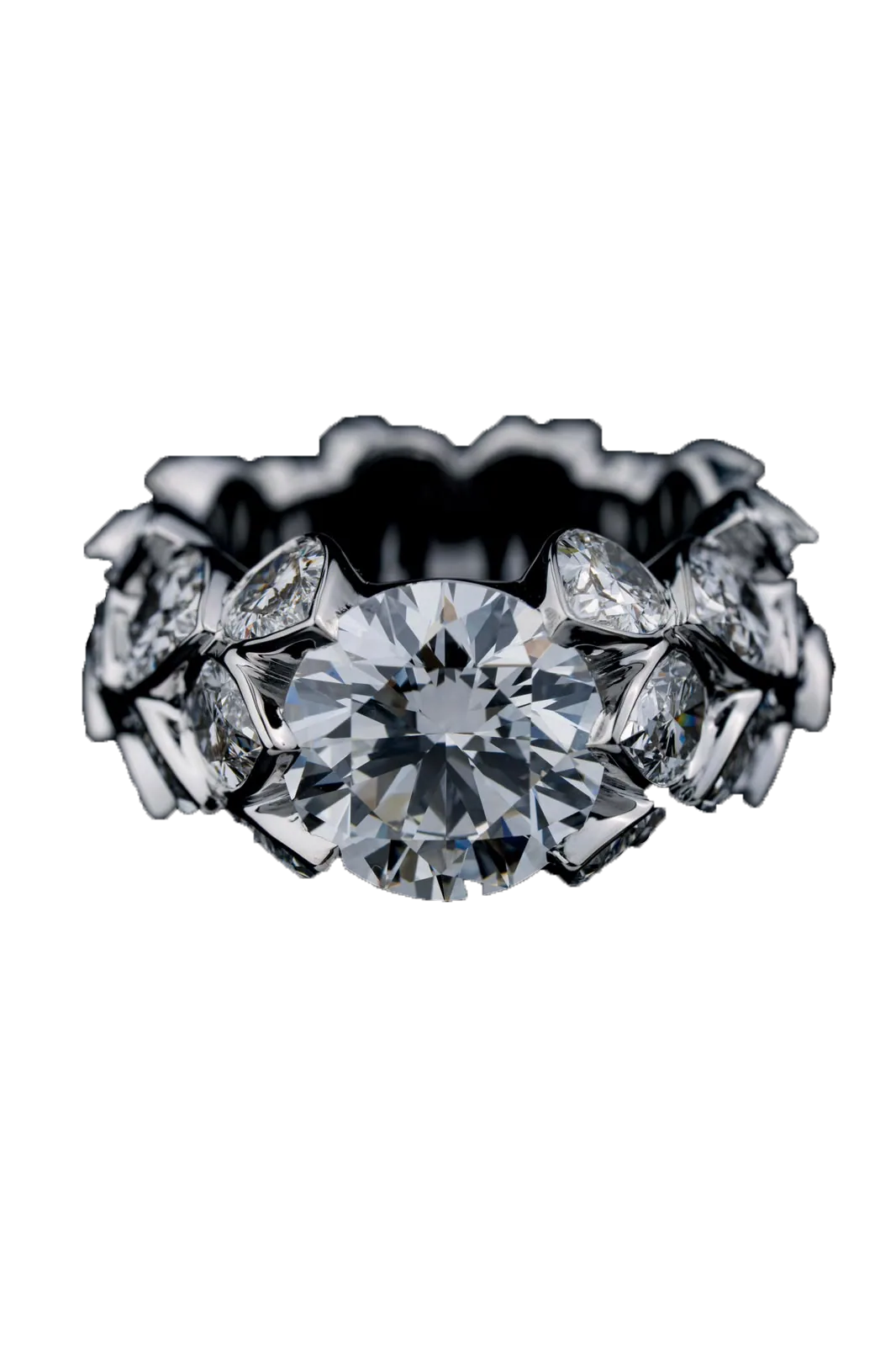 A white-gold ring cut out against near-black, a round brilliant centre stone above a full band of pear-cut diamonds.