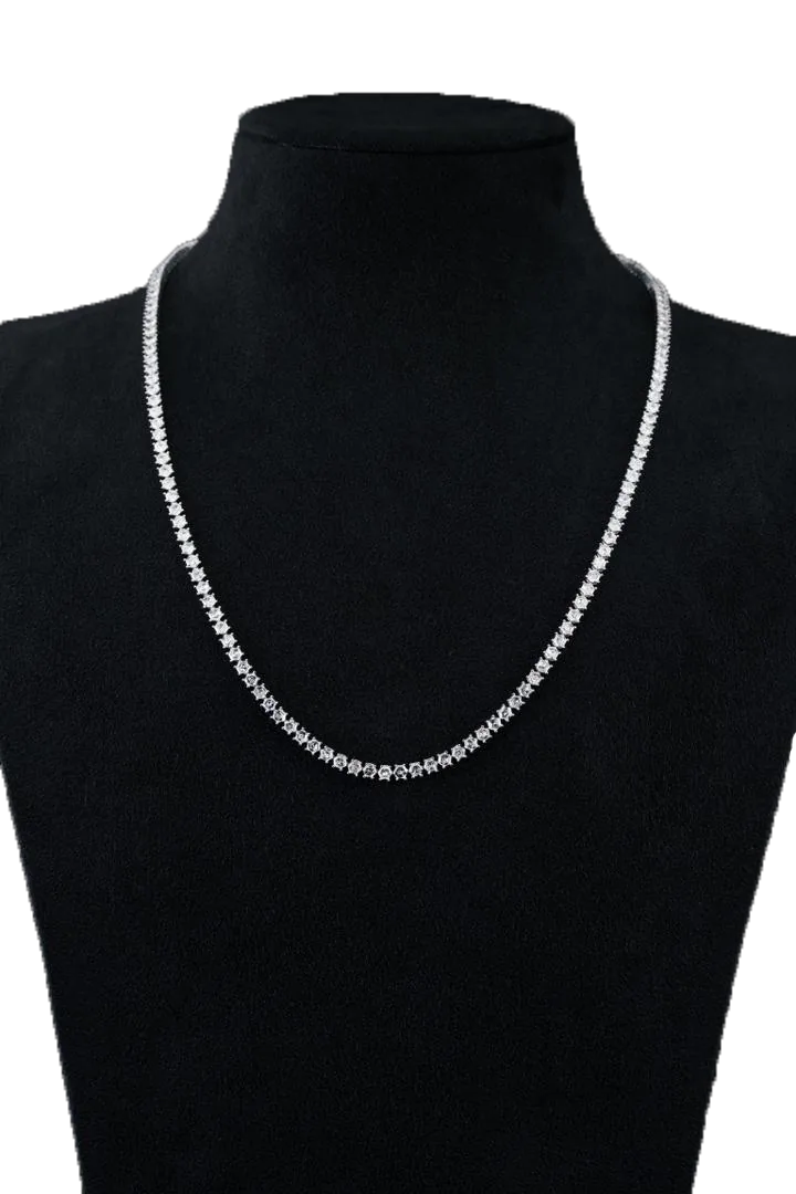 A white-gold diamond necklace on a black velvet bust, a single line of round, hexagon and marquise stones.