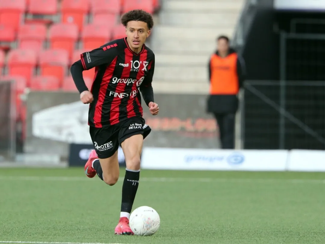 Salim Ben Seghir running with the ball in a red and black striped shirt.